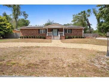 Charming single-story brick home featuring a gravel driveway, mature trees, and a welcoming front porch at 617 E Citrus St, Altamonte Springs, FL 32701