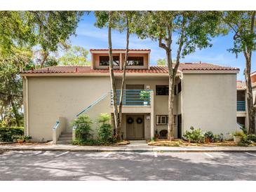 Charming condo featuring a red tile roof, blue railing accents, and a well-maintained exterior with mature trees at 1000 Winderley Pl # 140, Maitland, FL 32751