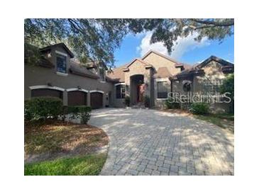 Elegant home with a paver driveway, three-car garage, and beautiful landscaping at 708 Palenci Ct, Winter Springs, FL 32708