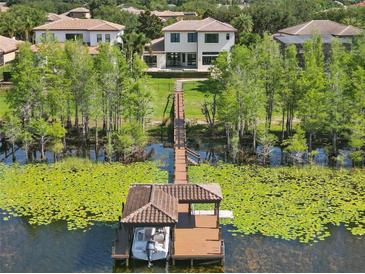 Stunning aerial view of a waterfront estate with a private dock and boat lift on a serene lake at 7624 Pointe Venezia Dr, Orlando, FL 32836