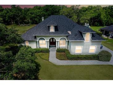 Inviting home featuring manicured landscaping, a gray roof, and arched windows at 878 Cardinal Pointe Cv, Sanford, FL 32771