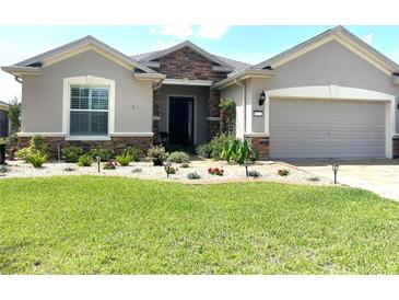 Charming home featuring a stone facade, well-manicured lawn, and a welcoming entrance with beautiful landscaping at 9872 Sw 75Th Street Rd, Ocala, FL 34481
