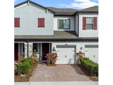 Charming townhome featuring a brick driveway, attached garage, well-maintained landscaping, and neutral-toned exterior at 308 Rustic Loop, Sanford, FL 32771