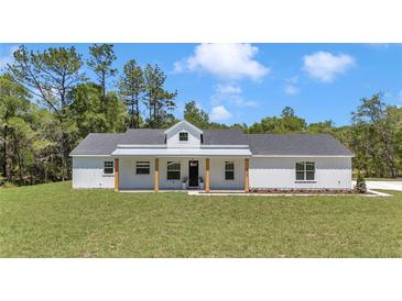 Beautiful single story home with a metal roof, covered porch with wood pillars, and a well manicured lawn at 6725 Sw 131St Cir, Ocala, FL 34481