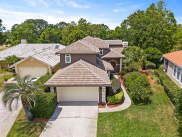 Attractive two-story home with a well-manicured lawn, tile roof, and an attached two-car garage at 14037 Fairway Willow Ln, Winter Garden, FL 34787