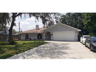 Charming single-story home with well-maintained lawn, long driveway, and attached two-car garage at 2404 Timbercreek E Loop, Lakeland, FL 33805