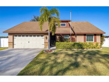 Charming single-story home with lush lawn, mature landscaping, and a two car garage at 241 Lake Thomas Dr, Winter Haven, FL 33880