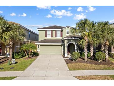 Inviting two-story home featuring a well-manicured lawn, mature palm trees and a neutral color palette at 5270 Wildwood Way, Davenport, FL 33837