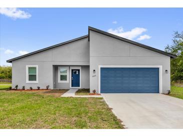 Beautiful single-story home featuring a blue garage door and well-manicured lawn at 5835 Sw 154 Lane Rd, Ocala, FL 34473