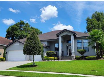 Beautiful single-story home with a well-manicured lawn, grey paint and large garage at 603 Sanctuary Golf Pl, Apopka, FL 32712