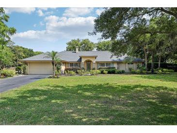 Charming single Gathering home with a lush green lawn and beautifully landscaped front yard at 7779 Lake Andrea Cir, Mount Dora, FL 32757