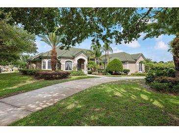 Charming single-story home boasting lush landscaping, a concrete driveway, and a well-maintained green roof at 9138 Pinnacle Cir, Windermere, FL 34786