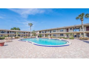 Community pool surrounded by brick pavers and lounge chairs in a well-maintained community on a sunny day at 5505 Hernandes Dr # 204, Orlando, FL 32808