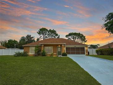 Charming single-story home boasts a well-manicured lawn and two-car garage, with a picturesque sunset backdrop at 10235 Summer Elm Ave, Clermont, FL 34711