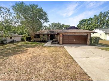 Charming single-story home with a well-maintained lawn, mature trees, and a two-car garage at 12610 Bay Hill Dr, Grand Island, FL 32735