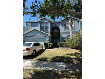 Charming two-story home with an attached garage and well-maintained front lawn and mature landscaping at 12822 Moss Park Ridge Dr, Orlando, FL 32832