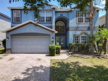 Charming two-story blue home with landscaped yard and brick driveway and a two-car garage at 12822 Moss Park Ridge Dr, Orlando, FL 32832