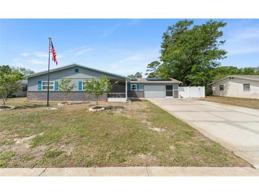 Charming single-story home with blue siding, brick accents, an American flag, and an attached two-car garage at 1328 Laurel Dr, Daytona Beach, FL 32117