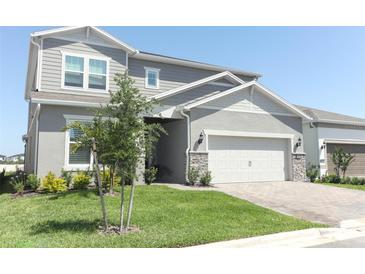 Charming two-story home with a manicured lawn, stone accents, and a two-car garage at 13617 Haulover Beach Ln, Orlando, FL 32827