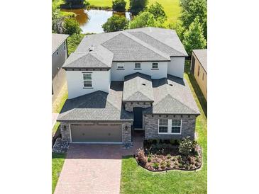A stunning aerial view of a two-story home showcasing its landscaped yard, covered entryway, and proximity to a pond at 1539 Wynell St, St Cloud, FL 34771