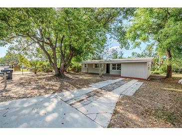 Single-story home featuring a neutral color, a long driveway, and a mature tree in the front yard at 4124 Caywood Cir, Orlando, FL 32810
