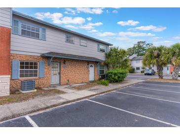 Inviting condo exterior featuring stone accents, neutral paint, blue shutters, and convenient parking at 7336 Daniel Webster Dr # 9, Winter Park, FL 32792