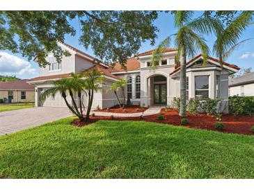 Charming home featuring a well-maintained lawn, mature landscaping, and a red tile roof at 11508 Delwick Dr, Windermere, FL 34786
