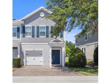 Charming two-story townhome featuring a one-car garage, blue shutters, and a welcoming brick driveway at 141 Mitchell Creek Way, Oviedo, FL 32765