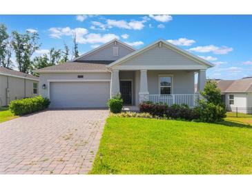 Charming one-story home featuring a well-manicured lawn and inviting covered front porch at 1757 Brush Cherry Pl, Ocoee, FL 34761