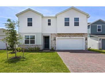 Charming two-story home with a brick paver driveway and a well-manicured lawn at 2055 Town Pasture Dr, Eustis, FL 32726