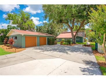 Home exterior featuring a two-car garage, large driveway, and lush greenery surrounding the property at 3085 Vest Rd, St Cloud, FL 34772
