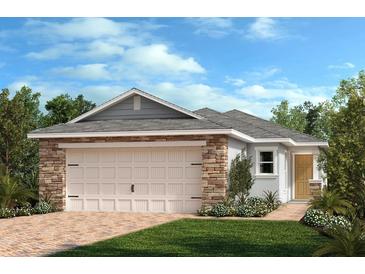 Charming single-story home featuring a two-car garage and beautifully landscaped front yard, blending stone and siding accents at 319 Sequoia Dr, Lake Wales, FL 33859