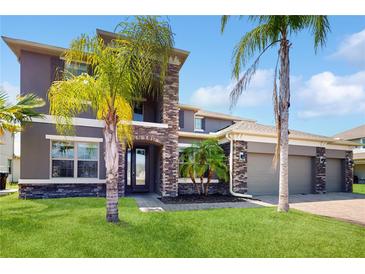 Elegant two-story home boasting a stone facade, three-car garage, and well-manicured lawn at 4002 Scarlet Branch Rd, Orlando, FL 32824