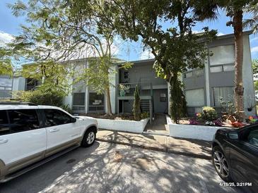 Condominium building with a gray exterior, staircase, and lush trees providing shade at 4328 Aqua Vista Dr # B, Orlando, FL 32839