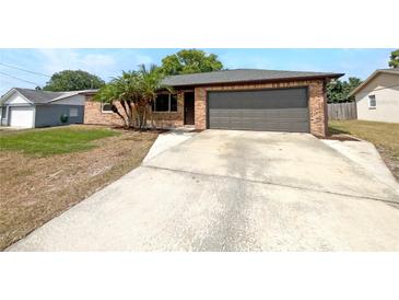 Charming single-story brick home featuring a well-maintained lawn, attached garage, and a concrete driveway at 52 Hydrangea Ln, Debary, FL 32713