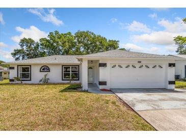 Charming single-story home featuring a two-car garage, well-maintained lawn, and modern architectural details at 3111 Pine Tree Dr, Edgewater, FL 32141