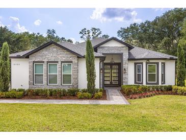 Charming single-story home with stone accents, manicured landscaping, and a modern glass front door at 16500 Magnolia Terrace Blvd, Montverde, FL 34756
