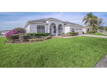 Beautiful single-story home with manicured lawn, arched entry, and lush landscaping with ample curb appeal at 409 Belfry Dr, Davenport, FL 33897