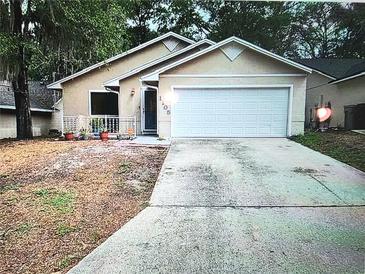 Charming single-story home with a two-car garage and inviting front porch with plants at 1105 Mill Run Cir, Apopka, FL 32703