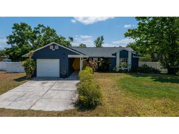 Charming single-story home with a well-manicured lawn, attached garage, and blue exterior paint at 1671 Judith Dr, Kissimmee, FL 34758