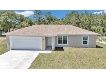 Inviting single-story home featuring a neatly manicured lawn, attached garage, and light beige exterior at 3914 Sw 161St Loop, Ocala, FL 34473