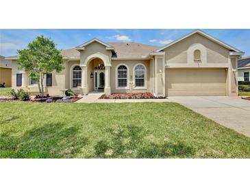 Charming single-story home with a well-manicured lawn, arched windows, and a two-car garage at 525 Hebrides Ct, Apopka, FL 32712