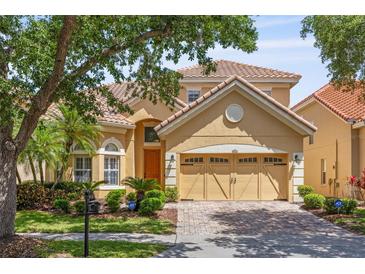Charming two-story home with a beautiful red-tile roof, brick paver driveway, and lush landscaping at 6857 Dolce St, Orlando, FL 32819