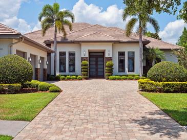 Stunning home exterior featuring a brick driveway, manicured landscaping, and a modern design at 8581 Lake Nona Shore Dr, Orlando, FL 32827