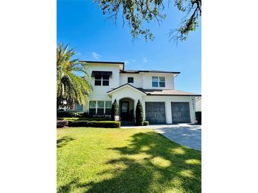Charming two-story home with a well-manicured lawn, palm trees, and a three car garage at 1690 Palm Ave, Winter Park, FL 32789