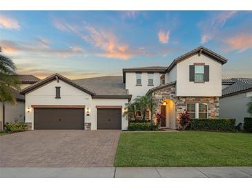 Beautiful two-story home showcasing stone accents, a well-manicured lawn, and a three-car garage at 8017 Chilton Dr, Orlando, FL 32836