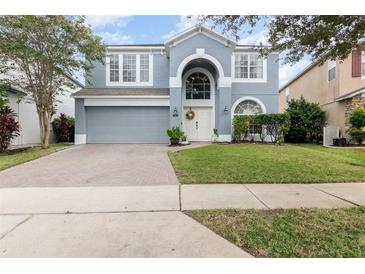 Charming two-story home featuring an arched entry, attached garage, and well-maintained landscaping at 12651 Winding Woods Ln, Orlando, FL 32832