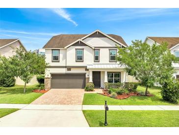 Charming two-story home with manicured lawn, lush landscaping, brick driveway, and a two car garage at 14883 Golden Sunburst Ave, Orlando, FL 32827