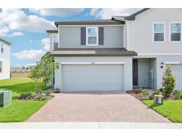 Charming townhome featuring a two-car garage, brick driveway, and well-manicured landscaping at 16430 Bird Of Paradise Ave, Clermont, FL 34714