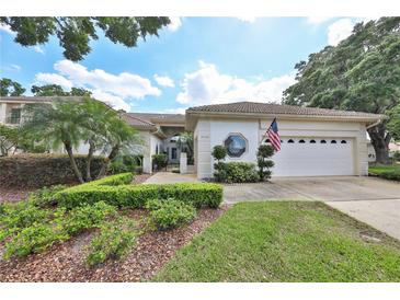 Charming one-story home featuring a tile roof, manicured landscaping, and a two-car garage at 2446 Sweetwater Country Club Dr, Apopka, FL 32712